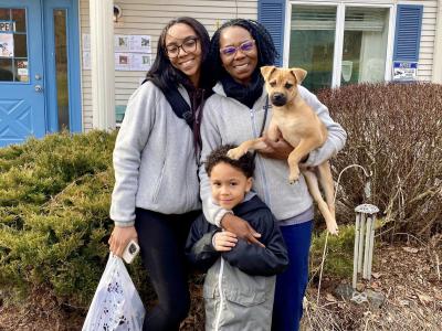 Two people and a child with a tan puppy whose front foot is on the child's head